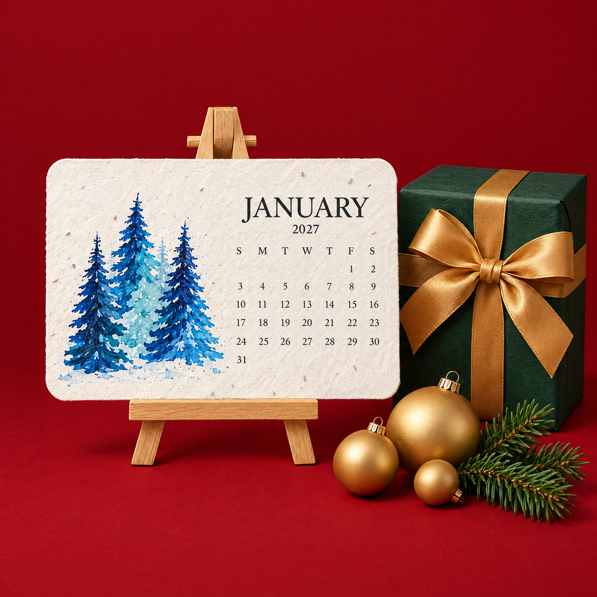 The January 2027 seed paper calendar on its easel beside a wrapped Christmas present and gold baubles